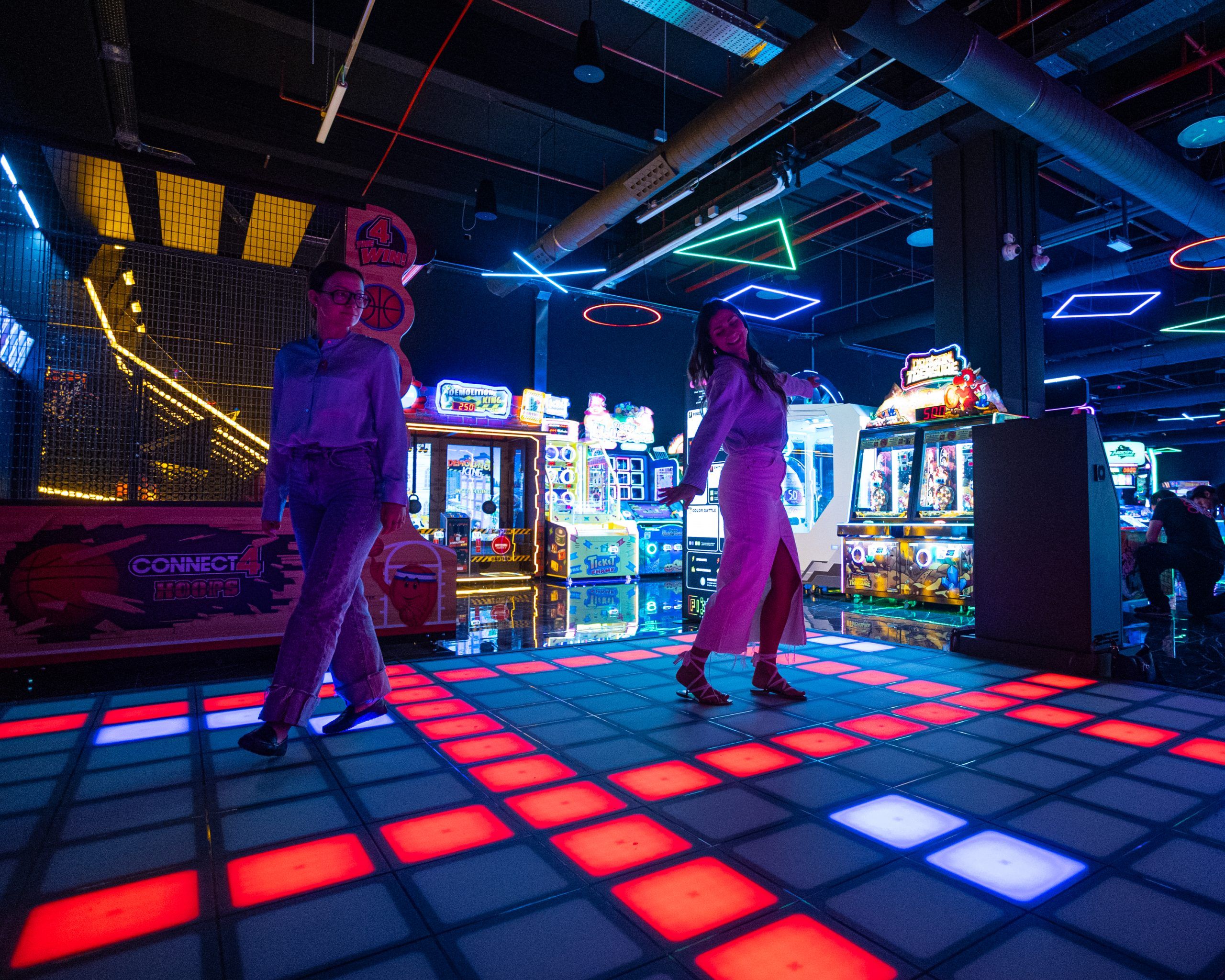 Persone che giocano all'interno della scenografia creata dal nostro progetto di illuminazione per LOG Vimercate, un ambiente dove la luce modella l'esperienza