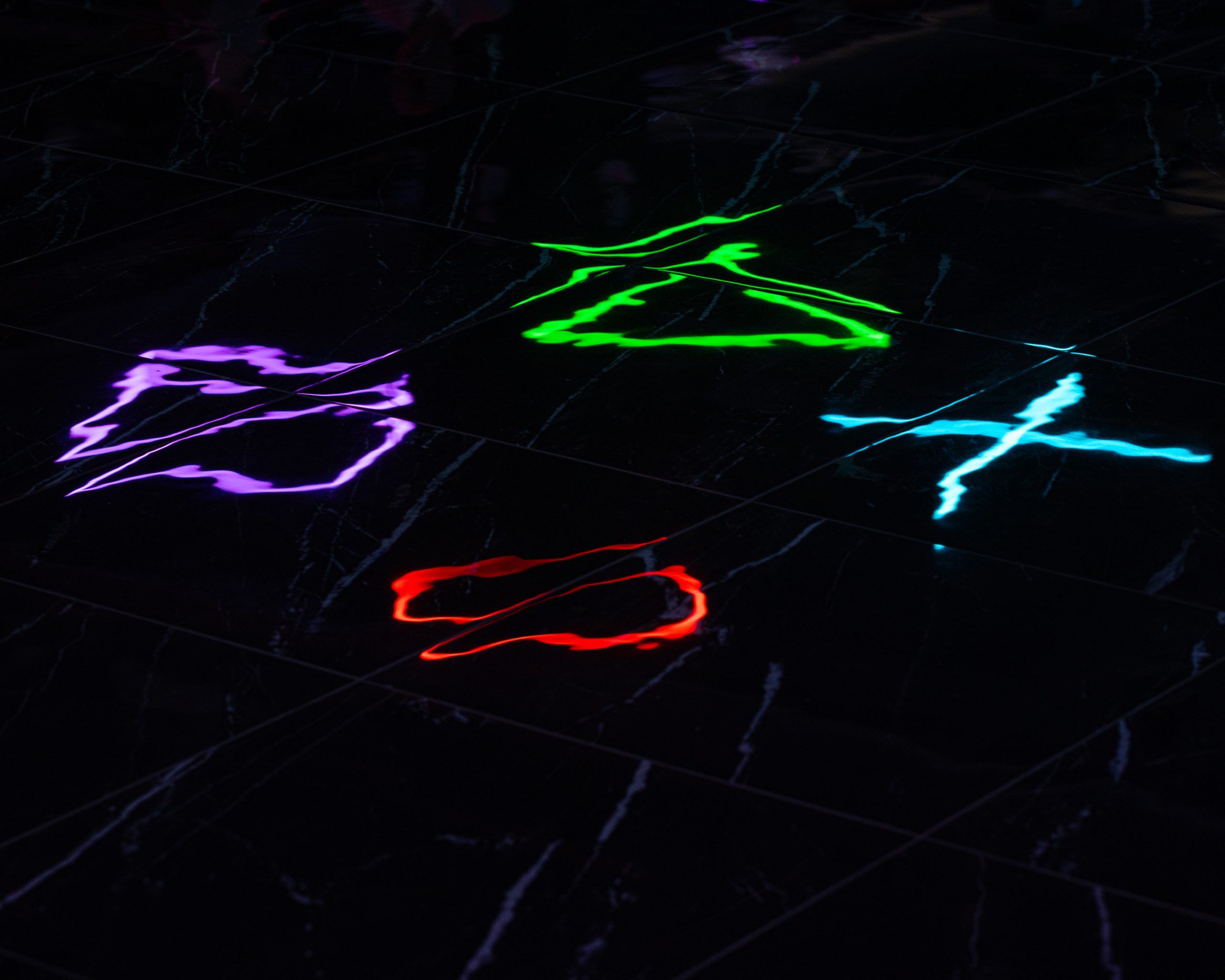 Effetto immersivo creato dai riflessi delle luci LED colorate sul pavimento in marmo nero lucido della sala giochi LOG a Vimercate.