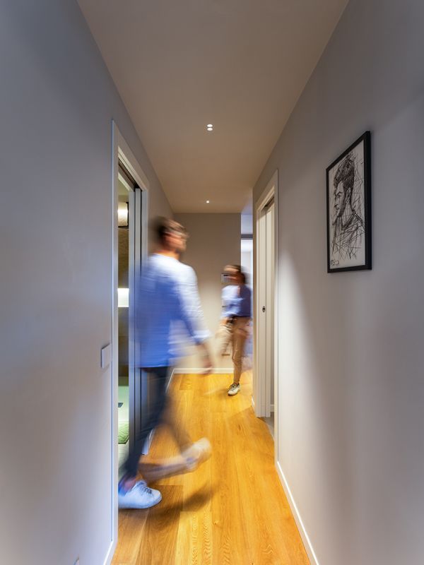 Corridoio illuminato con faretti da soffitto e due persone che camminano