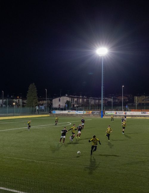 Foto di un campo da calcio durante una partita, illuminato dai pali della luce