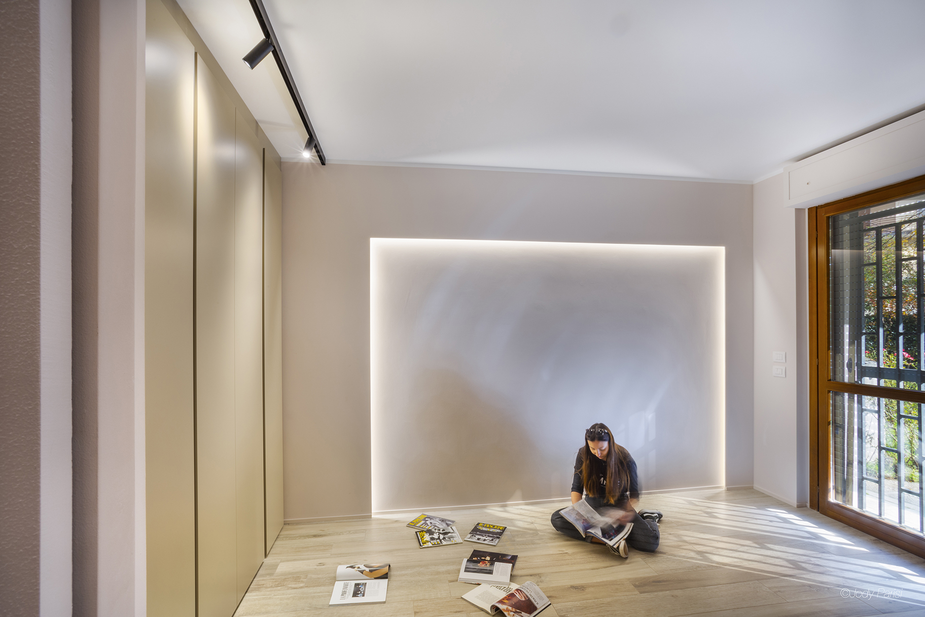 Foto di una stanza con una ragazza seduta sul pavimento che sfoglia una rivista