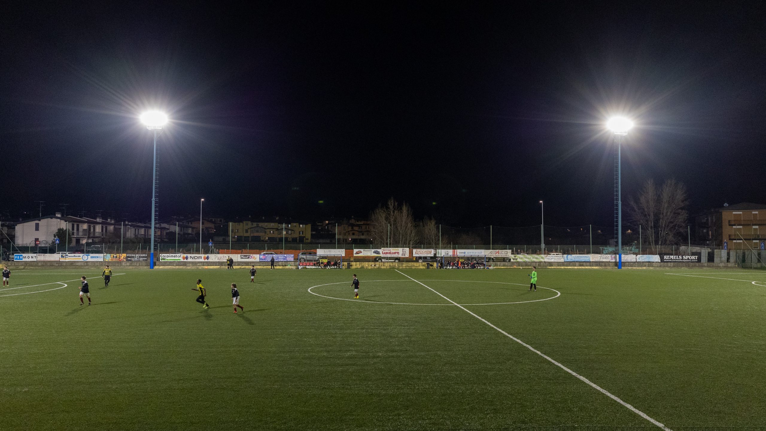 Foto di un campo da calcio durante una partita, illuminato dai pali della luce