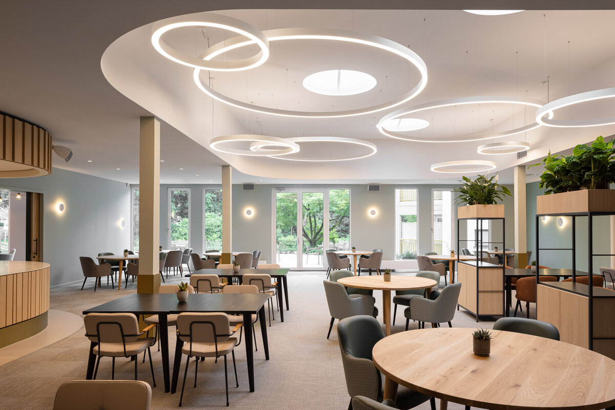 Lampade a sospensione di forma circolare illuminano una sala piena di tavoli e sedie