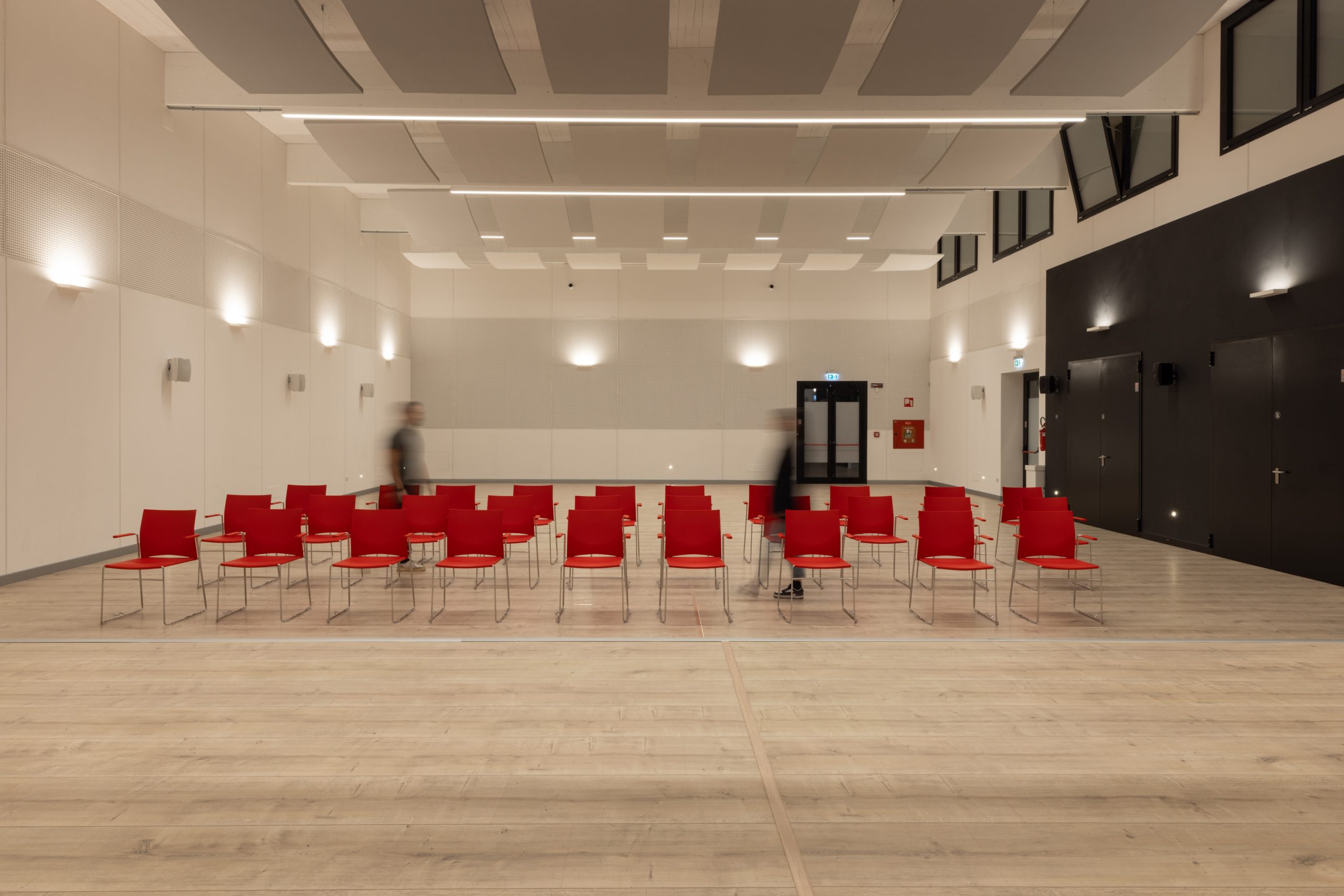 Aula magna illuminata con due persone che camminano