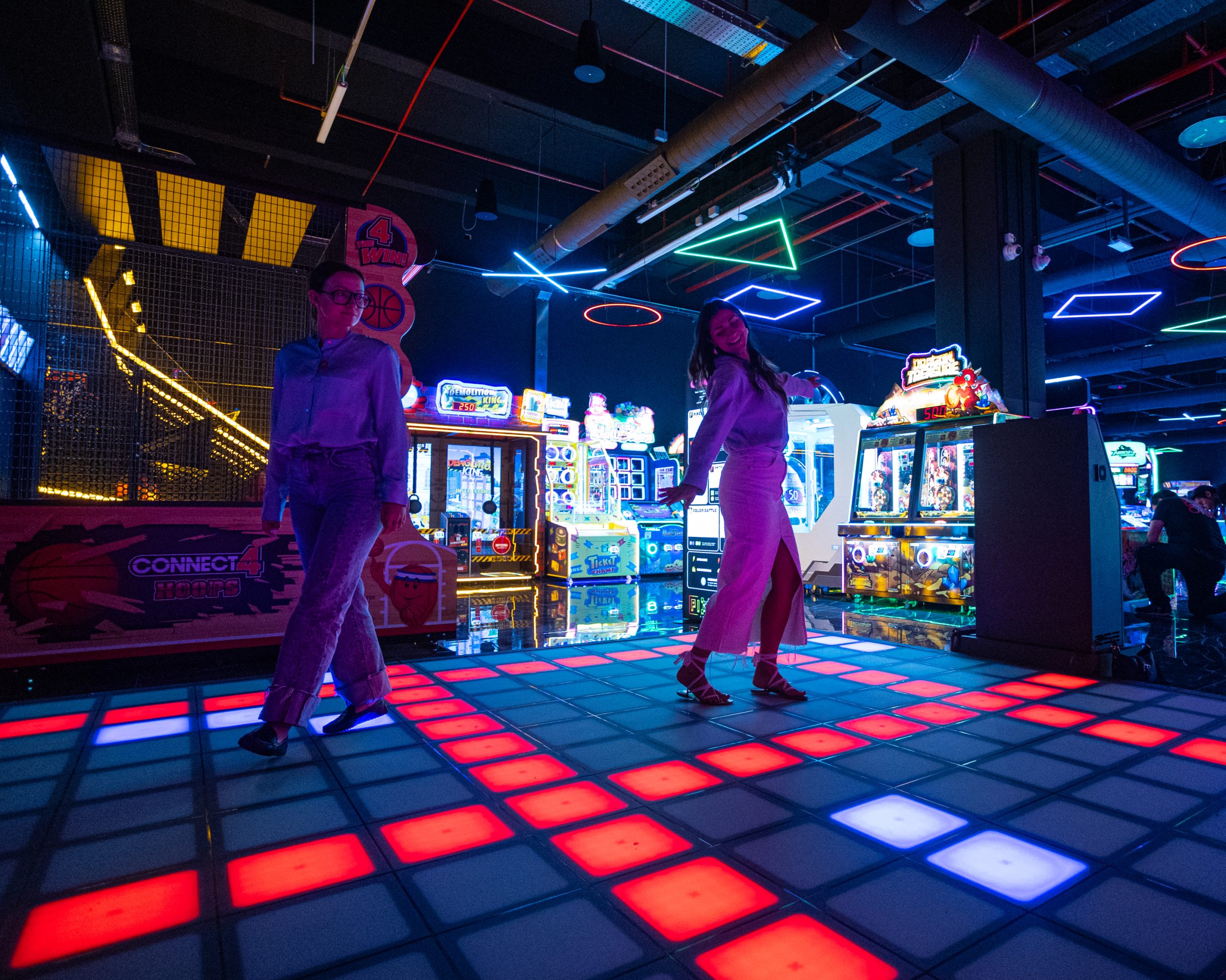 Persone che giocano all'interno della scenografia creata dal nostro progetto di illuminazione per LOG Vimercate, un ambiente dove la luce modella l'esperienza