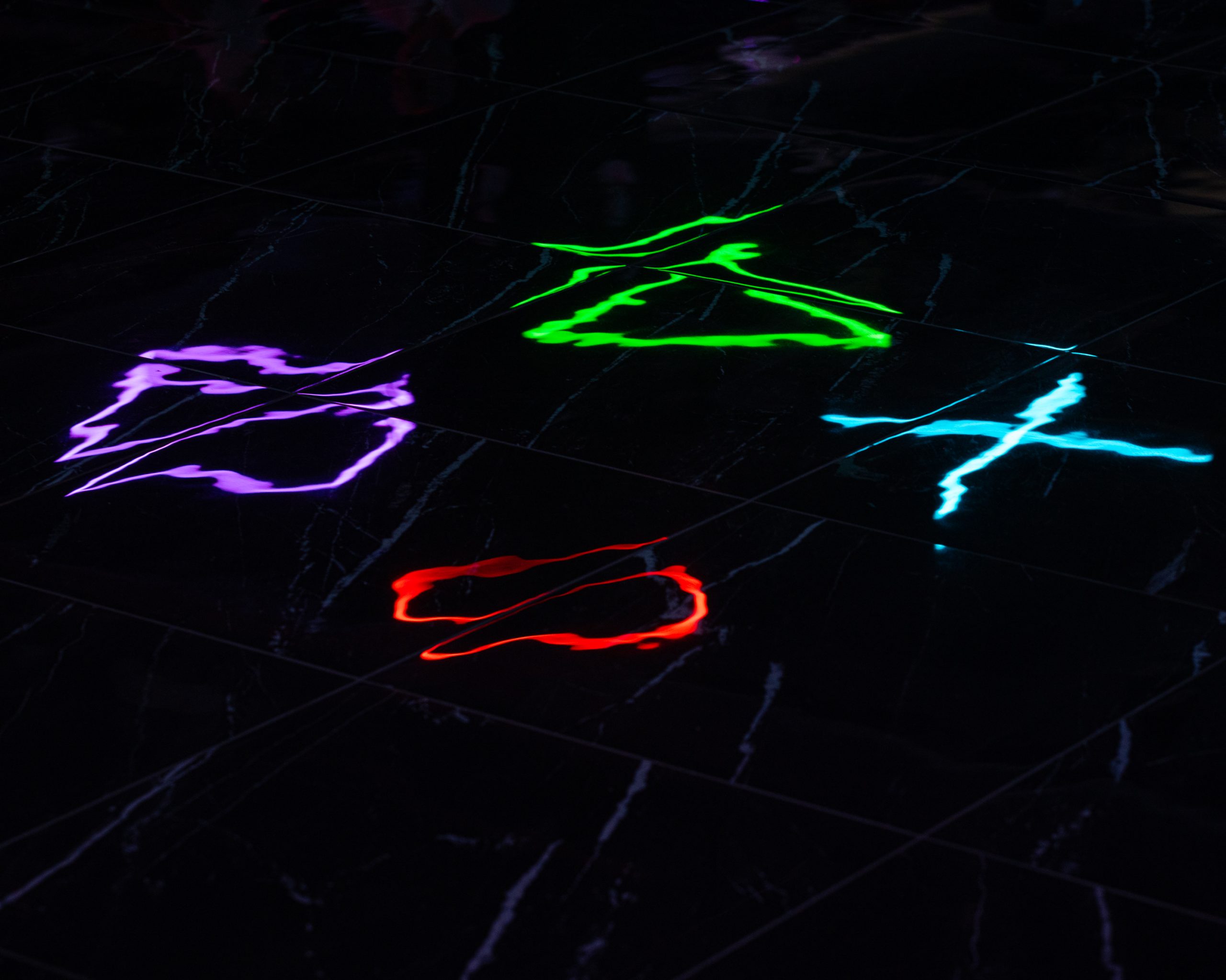 Effetto immersivo creato dai riflessi delle luci LED colorate sul pavimento in marmo nero lucido della sala giochi LOG a Vimercate.