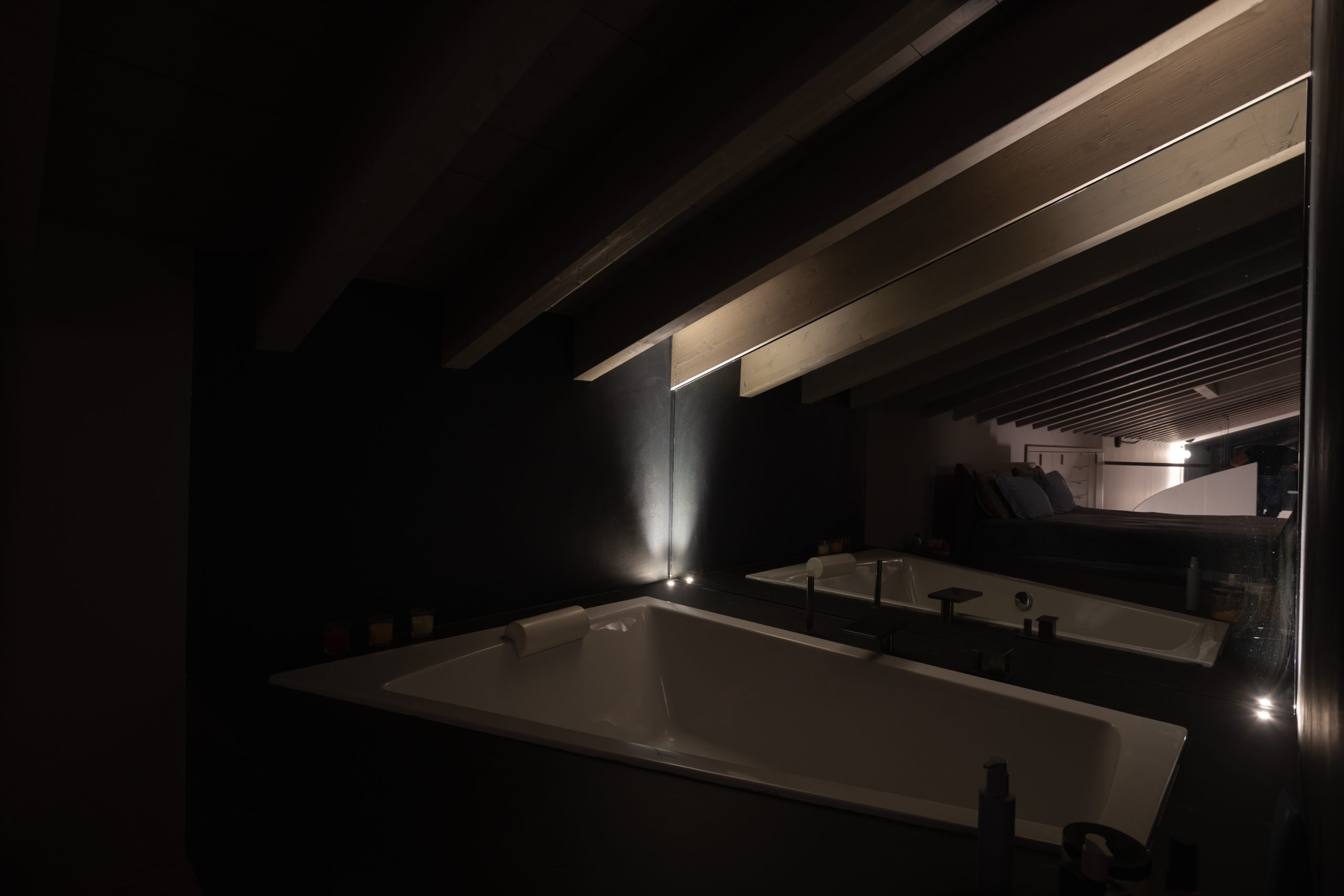 Bagno con travi a vista illuminato con luce indiretta e diffusa.
