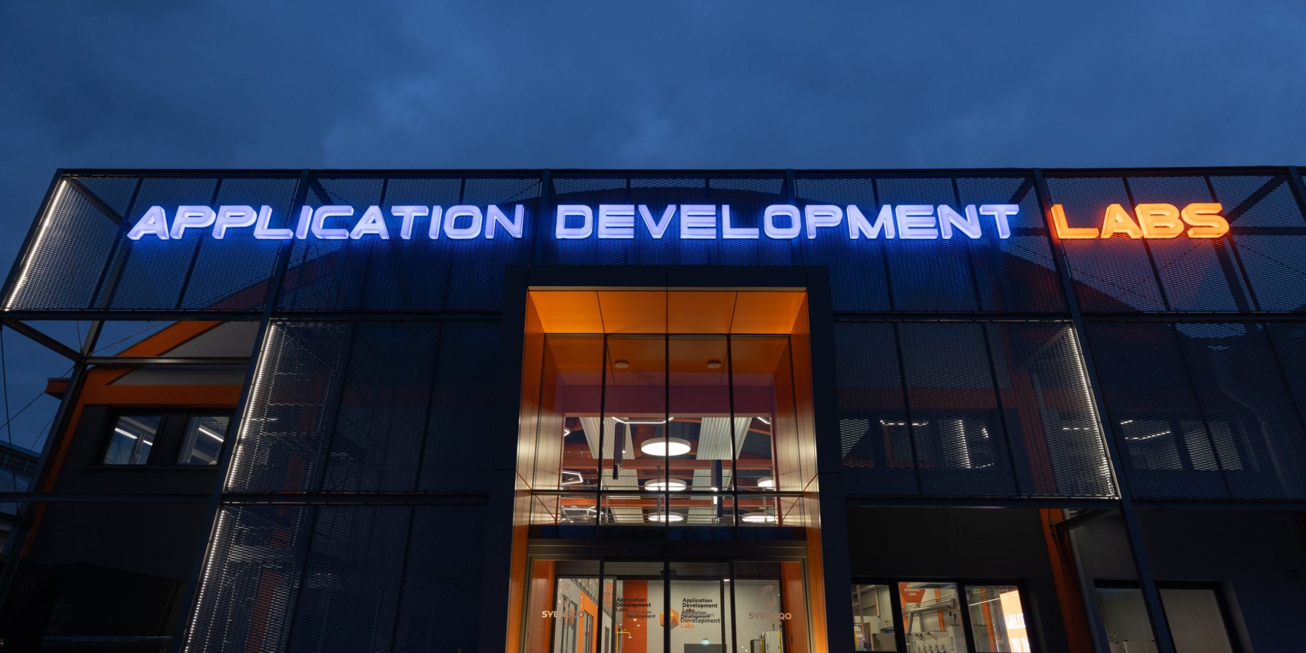 Facciata del capannone industriale di Solvey, con un'insegna a led di colore blu e arancio