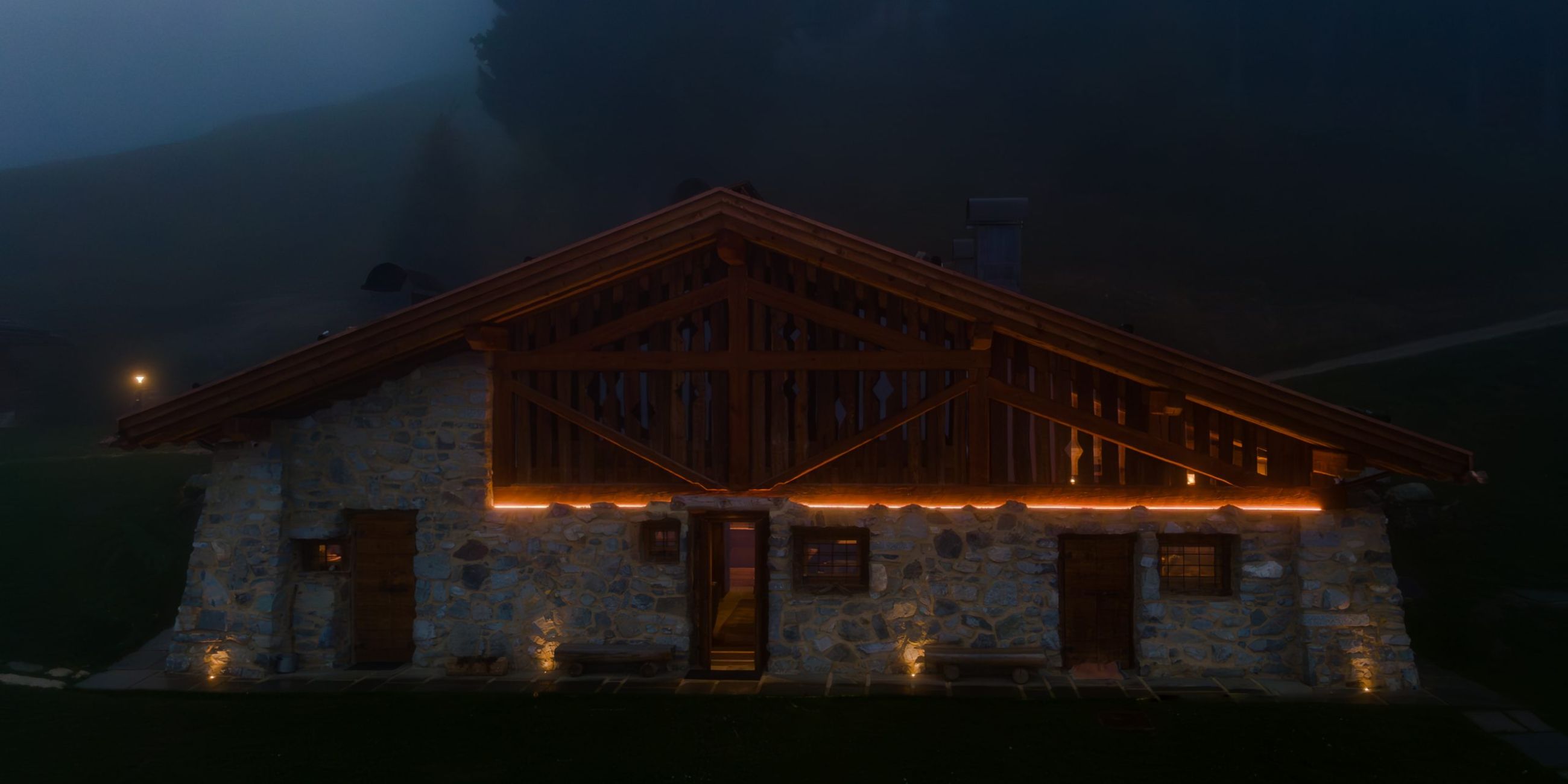 Illuminazione della facciata esterna di una baita di montagna in trentino