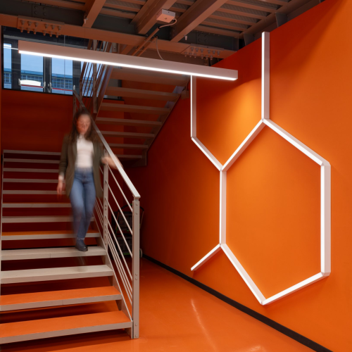 Persona scende le scale e illuminazione con forma geometrica da parete 