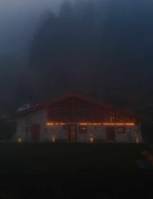 La facciata illuminata di una baita tra le montagne del trentino