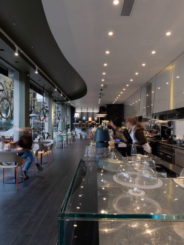 Foto di un locale/caffetteria che mostra il bancone on le cose da mangiare e l'illuminazione data dai faretti sul soffitto