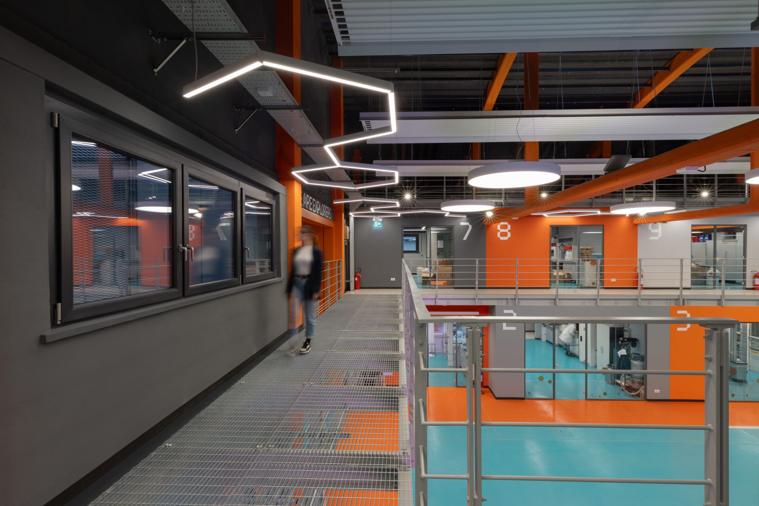 Foto di una persona che cammina in un magazzino illuminato da lampade a sospensione