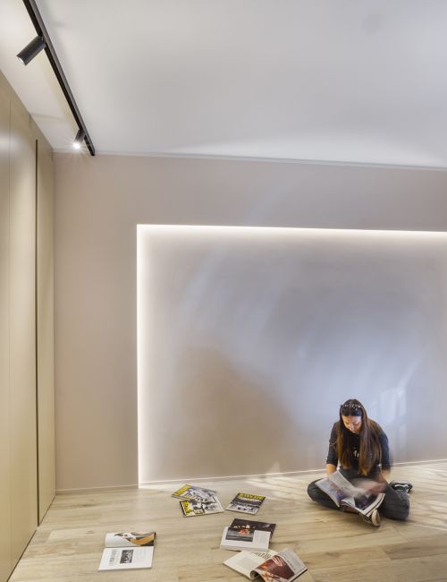 Foto di una stanza con una ragazza seduta sul pavimento che sfoglia una rivista