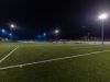 Foto di un campo da calcio durante una partita, illuminato dai pali della luce