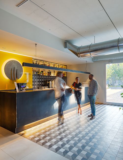 Zona bar di un bistrot con un'insegna appesa ad un muro giallo