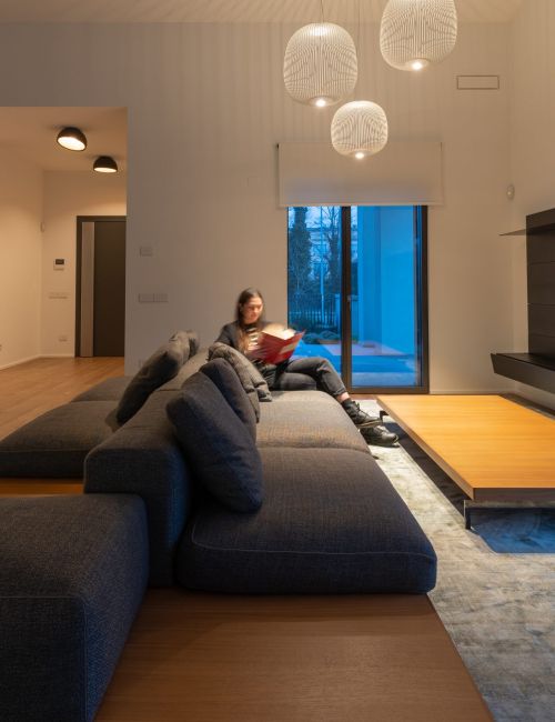 Salotto di una villa con illuminazione a sospensione e ragazza seduta sul divano