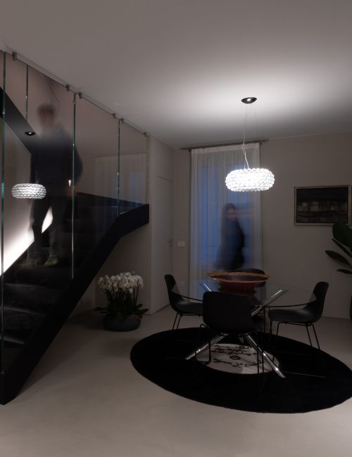 La zona pranzo di un moderno appartamento illuminato con sospensione in vetro.