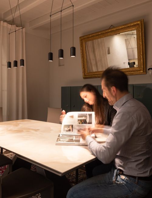 Uomo e donna seduti ad un tavolo illuminato da una sospensione