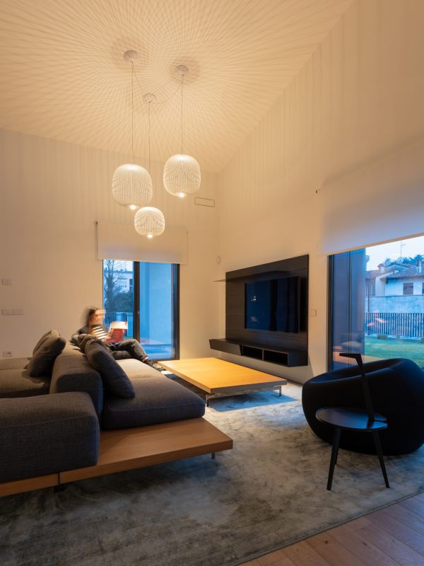 Salotto di una villa con illuminazione a sospensione e ragazza seduta sul divano