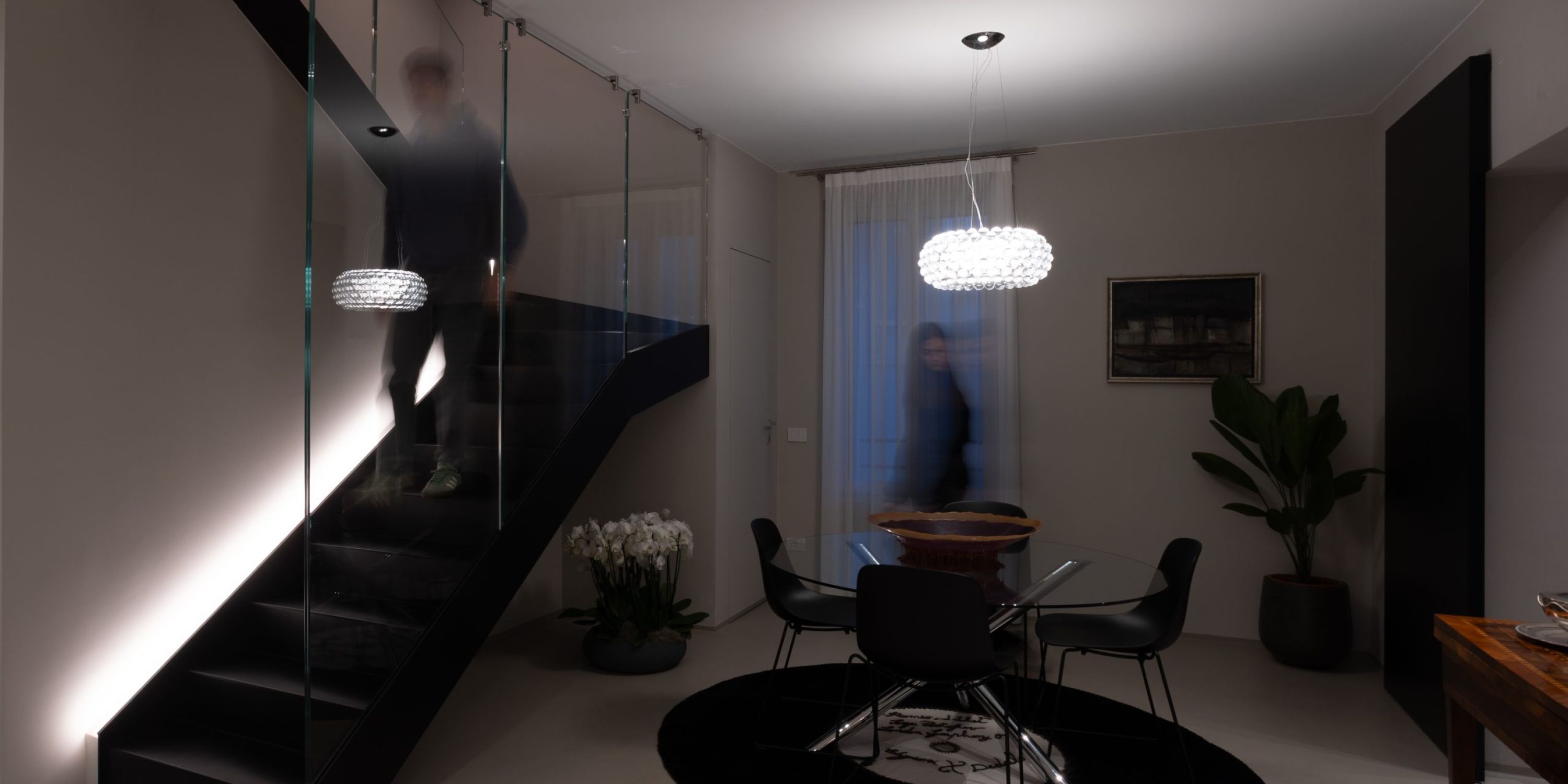 La zona pranzo di un moderno appartamento illuminato con sospensione in vetro.