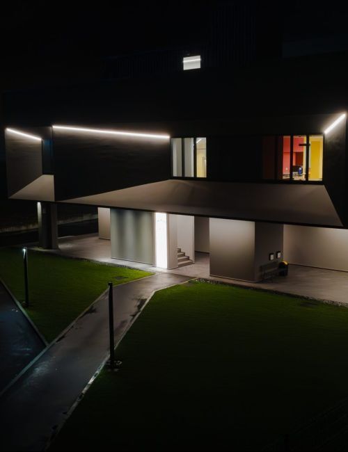 Fotografia scattata con un drone in cui figura la facciata di uno stabilimento industriale illuminato esternamente e anche internamente